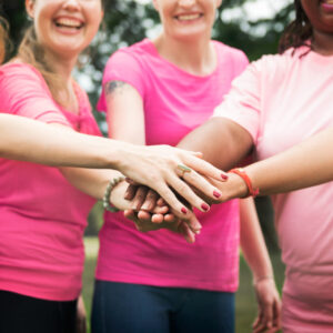Imagem grupo de mulheres vestidas de rosa e com as mãos unidas, simbolizando a luta contra o câncer de mama