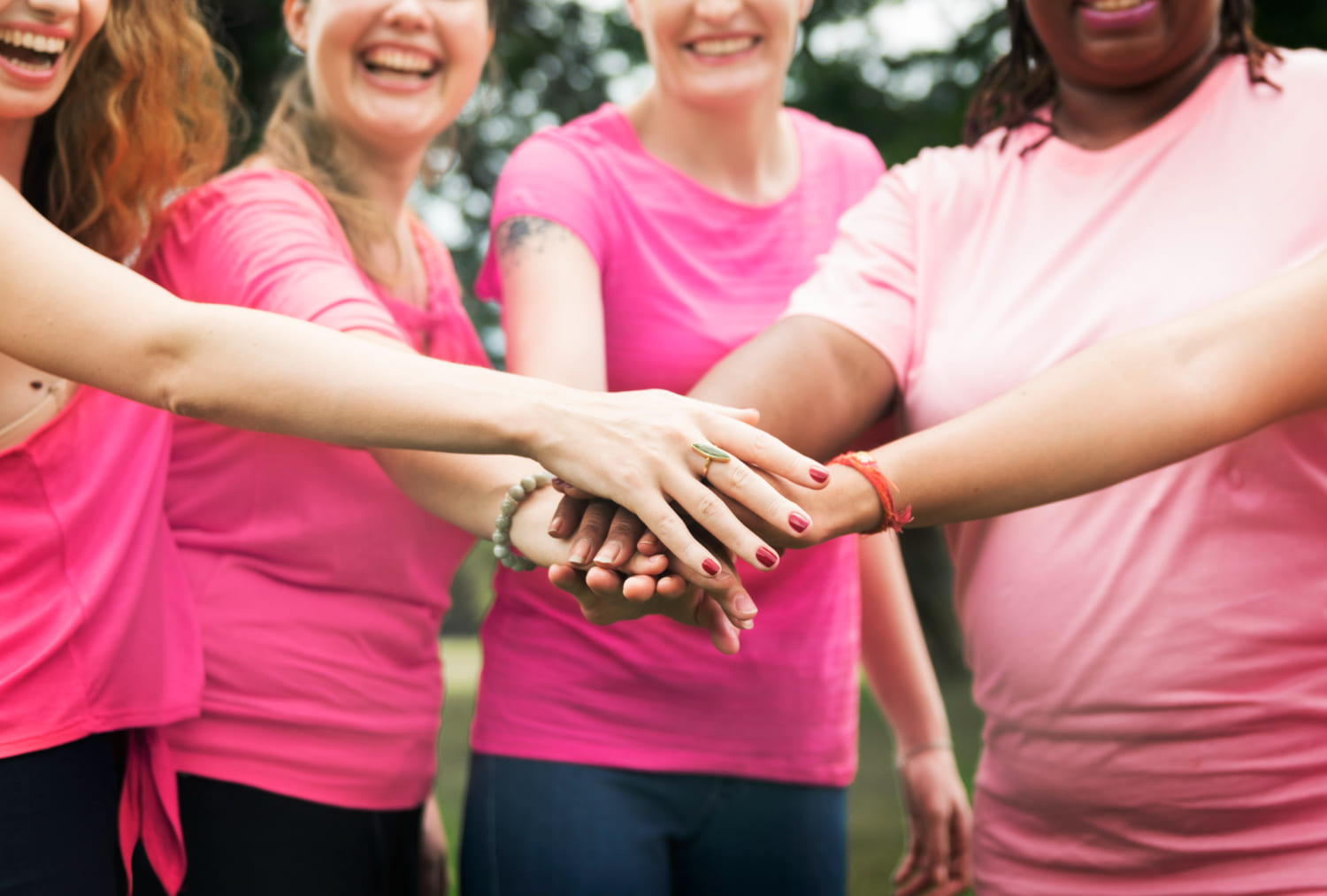 Imagem grupo de mulheres vestidas de rosa e com as mãos unidas, simbolizando a luta contra o câncer de mama 