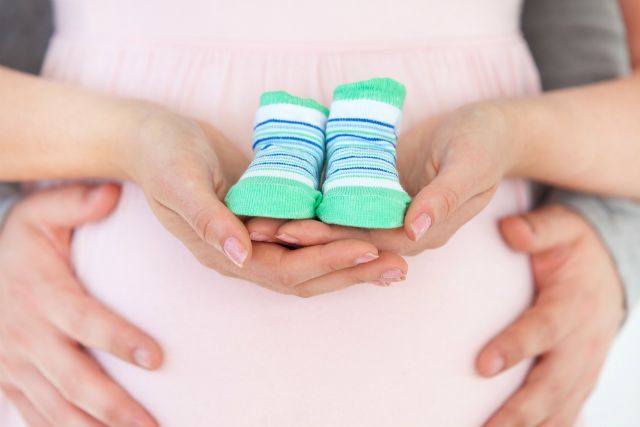 barriga de grávida segurando um sapato de bebê