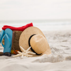 imagem de chinelo, chapéu e bolsa de praia na areia